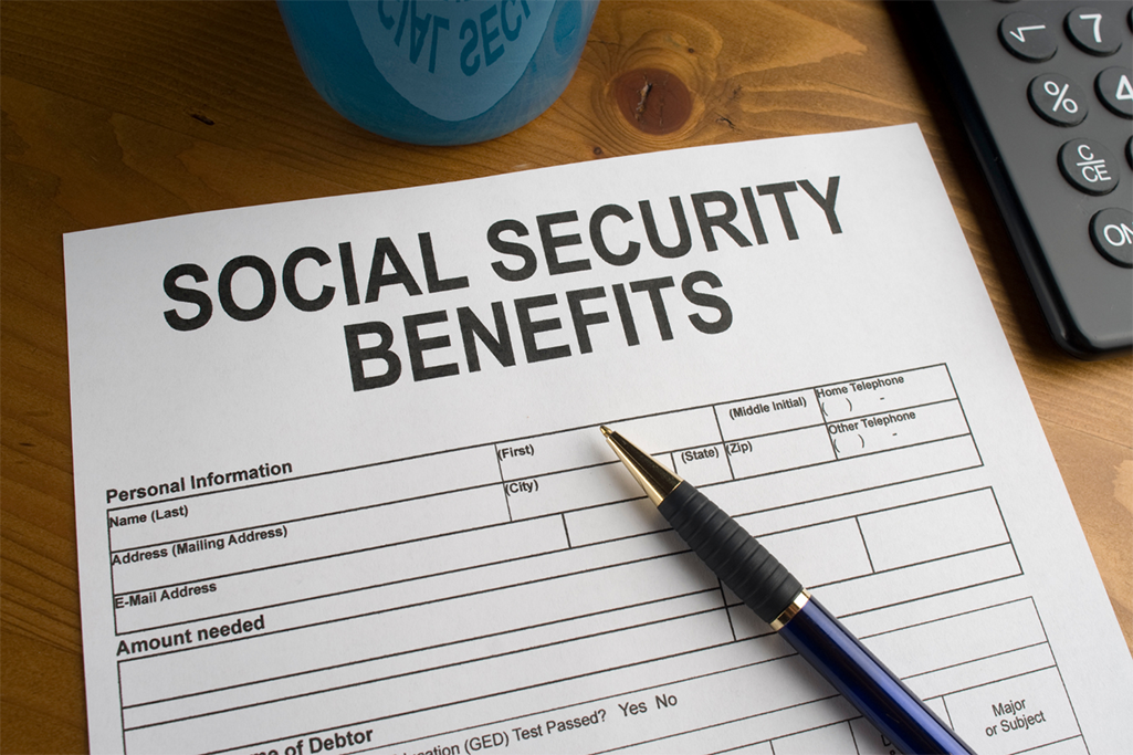 A social security benefit form is laying on a desk with a pen on top.