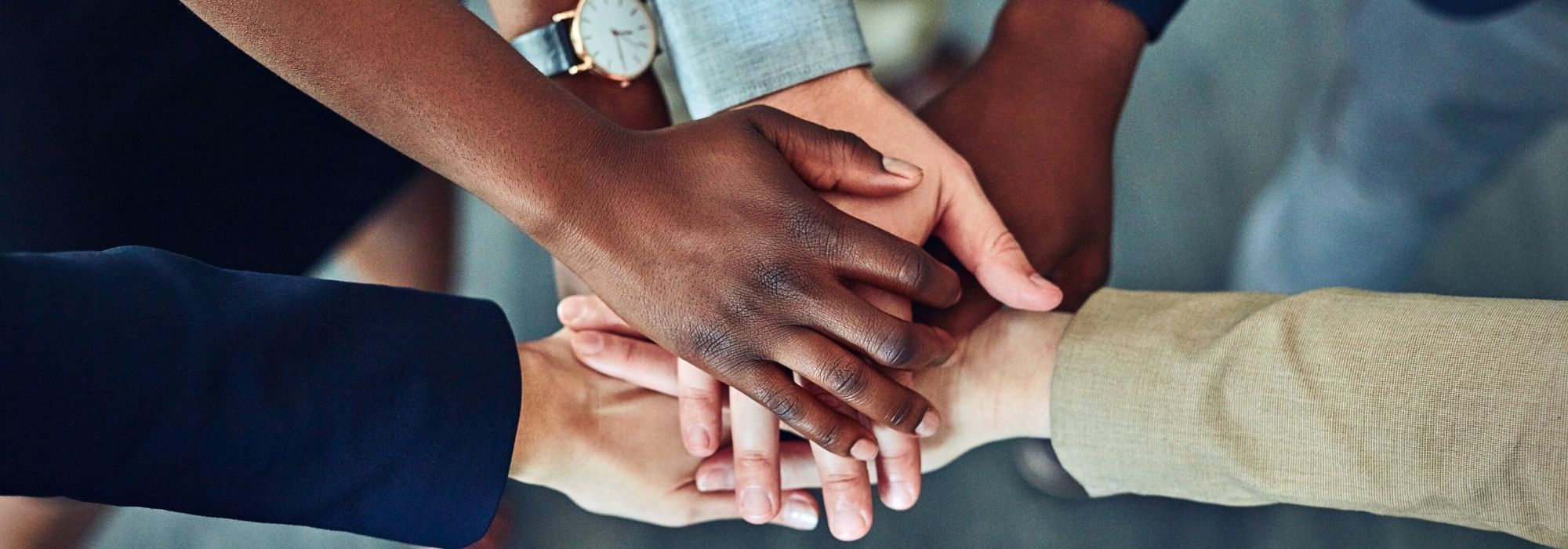 Multiple hands in the center of a group for a team handshake