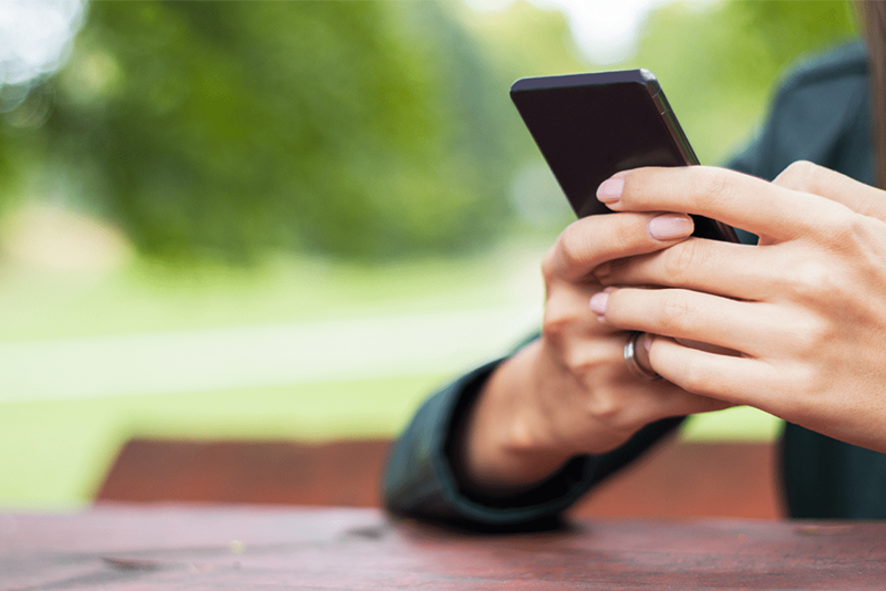As mãos de uma mulher seguram um telemóvel e enviam mensagens de texto.