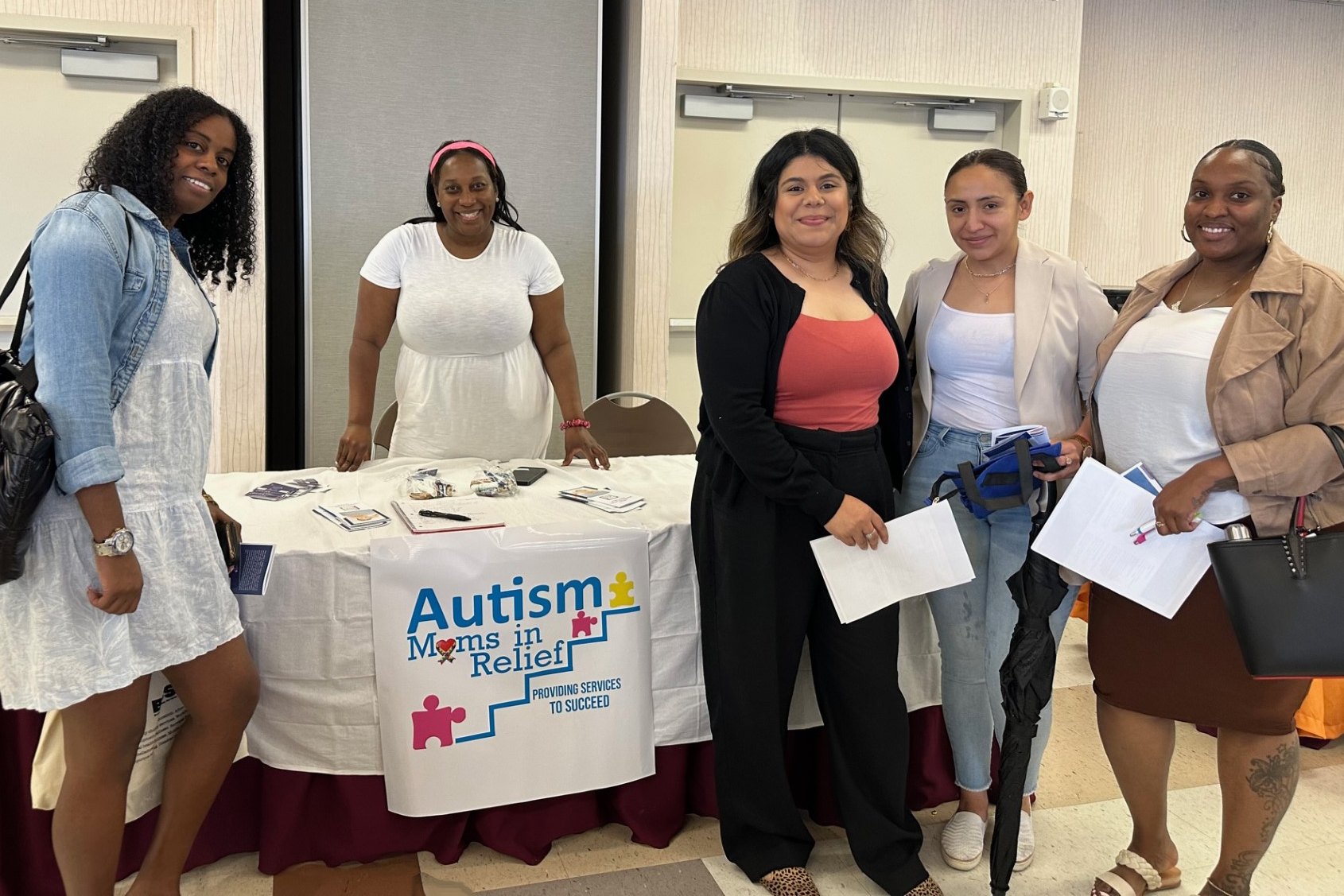 Five women stand near a promotional table for Autism.