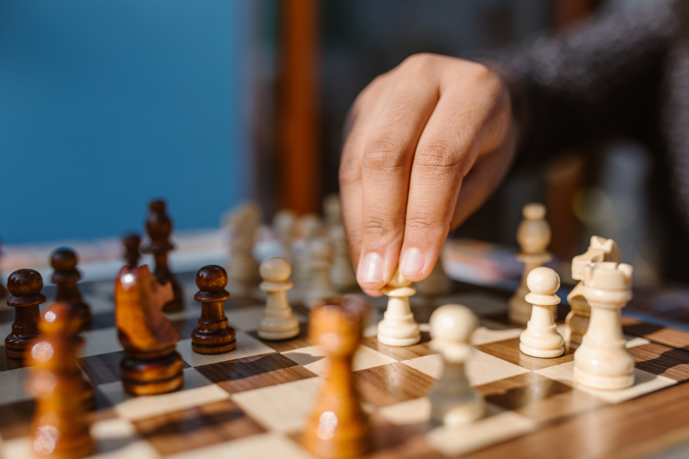 A hand is moving a pawn piece on a chessboard.