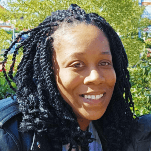 An independent woman: A Black woman in dreads smiles in the sunshine.