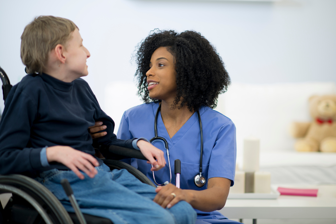 Provider Educational Webinars: A nurse bends down to talk to a young man in a wheelchair.
