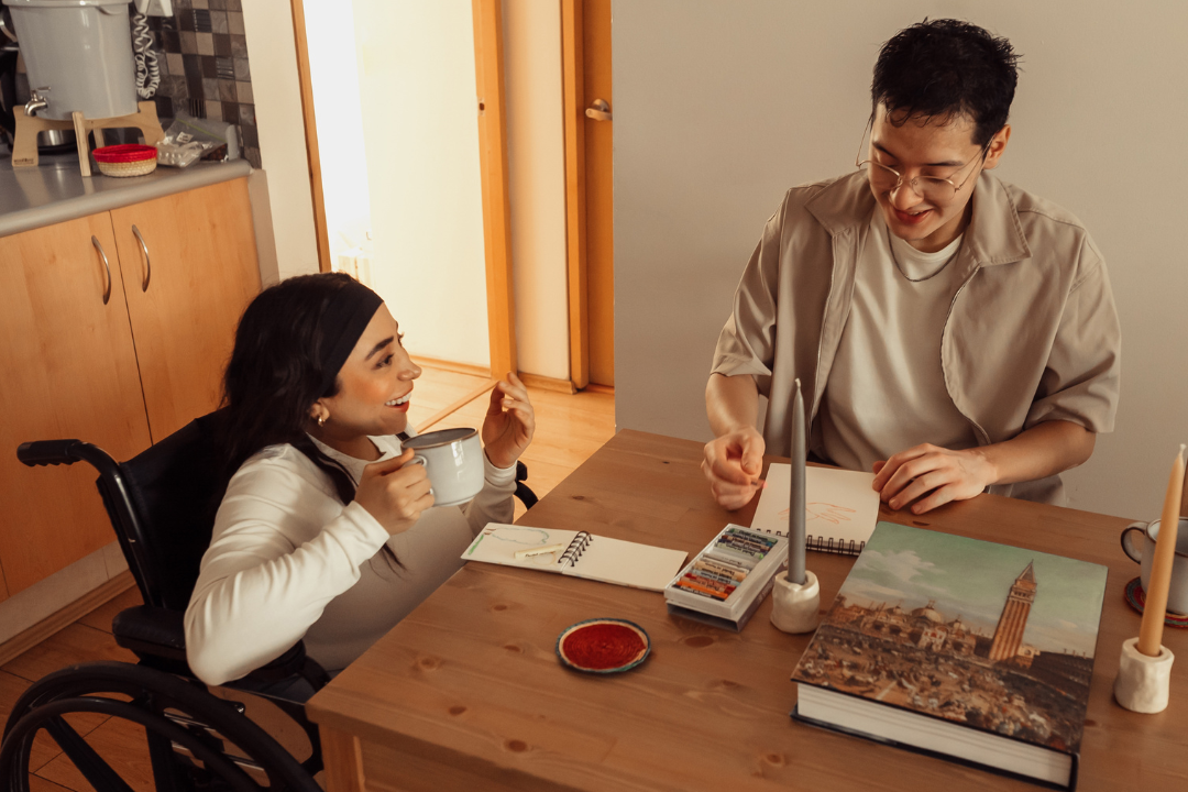 A young woman has coffee with a partner at a dining room table.