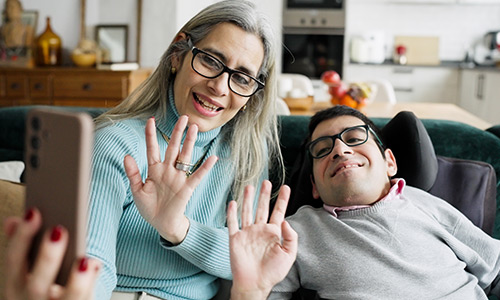 man and woman looking at phone and waving